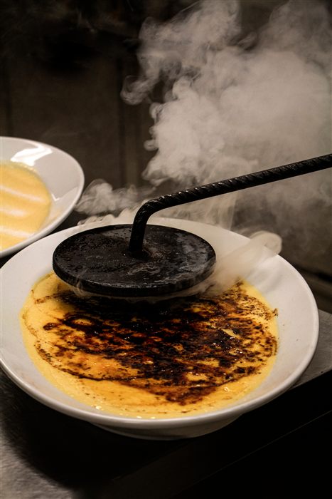 Crème brûlée being caramelised with a hot iron