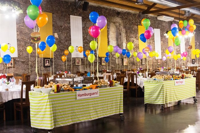 Party hall decorated with balloons and food stations